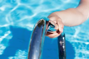 Female's hand holding a handrail in swimming pool
